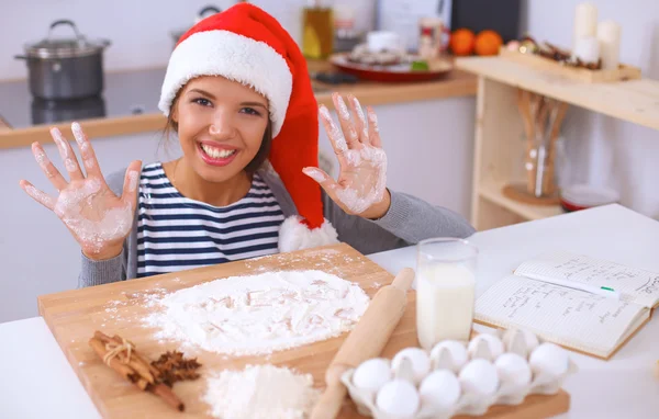Χαρούμενη νεαρή γυναίκα χαμογελώντας χαρούμενη διασκεδάζοντας με τις Χριστουγεννιάτικες προετοιμασίες φορώντας το καπέλο του Άη Βασίλη — Φωτογραφία Αρχείου