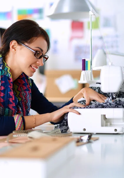 Mujer joven cosiendo sentado en su lugar de trabajo — Foto de Stock