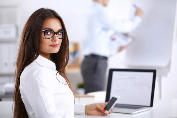 Aantrekkelijke zakenvrouw zit op het bureau in het kantoor — Stockfoto