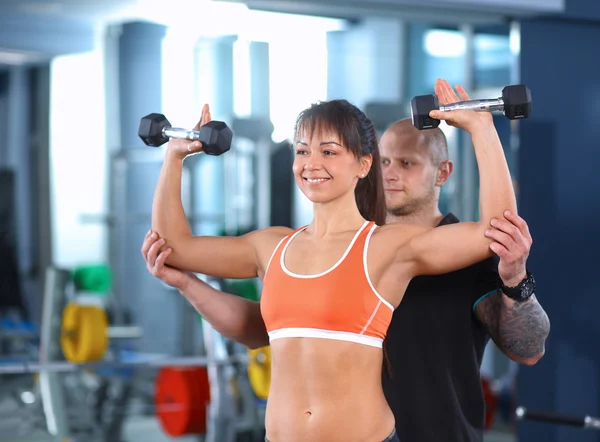 Hermosa mujer en el gimnasio haciendo ejercicio con su entrenador — Foto de Stock