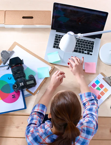 Vrouwelijke fotograaf zittend op het bureau met laptop — Stockfoto