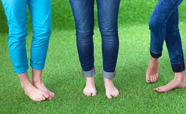 Tres mujeres con los pies desnudos de pie en la hierba — Foto de Stock