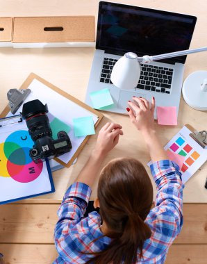 Masada dizüstü bilgisayarla oturan kadın fotoğrafçı.