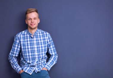 Gri arka plan üzerinde izole gülümseyen genç adam portresi