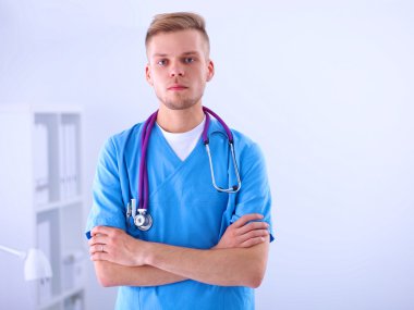 Steteskoplu doktor ayakta, çapraz kollu, beyaz arka planda izole.