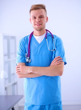 Steteskoplu doktor ayakta, çapraz kollu, beyaz arka planda izole.