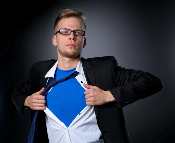 Young businessman acting like a super hero and tearing his shirt, isolated on gray background — Stock Photo, Image