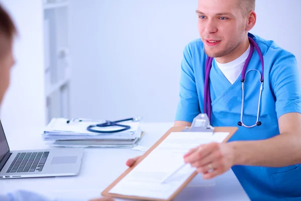 Doctor macho dando carpeta de paciente con papel en su oficina, aislado —  Fotos de Stock
