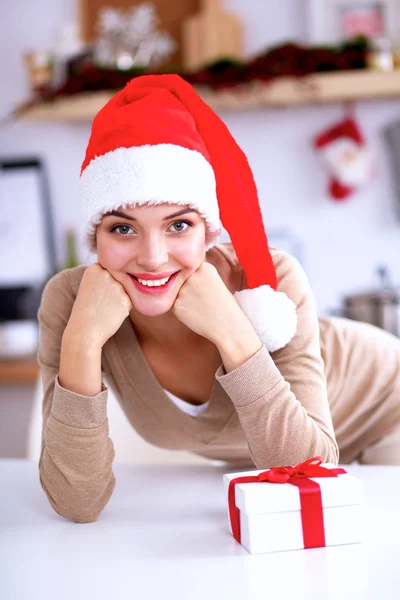 Lächelnde junge Frau in der Küche, isoliert auf weihnachtlichem Hintergrund — Stockfoto