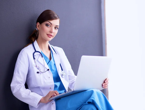 Médica feminina trabalhando sentada em fundo cinza — Fotografia de Stock