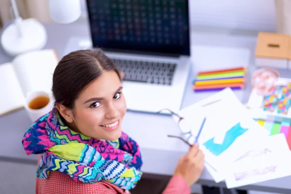 Young attractive female fashion designer working at office desk, drawing while talking on mobile — Stock Photo, Image