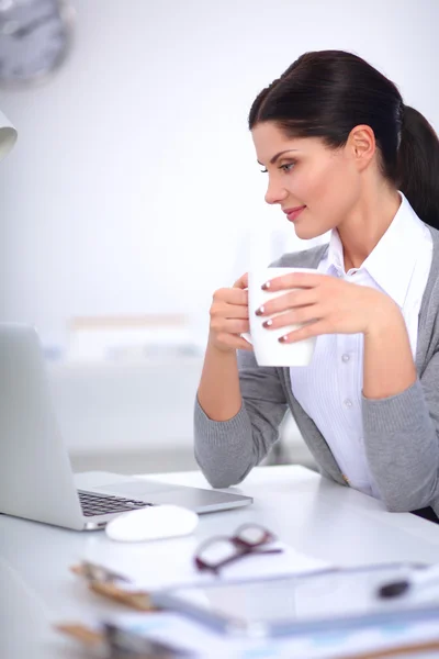 Joven mujer de negocios sentada en el escritorio con taza en la oficina — Foto de Stock