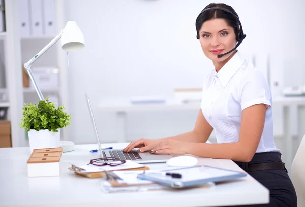 Ritratto di bella donna d'affari che lavora alla scrivania con auricolare e laptop — Foto Stock