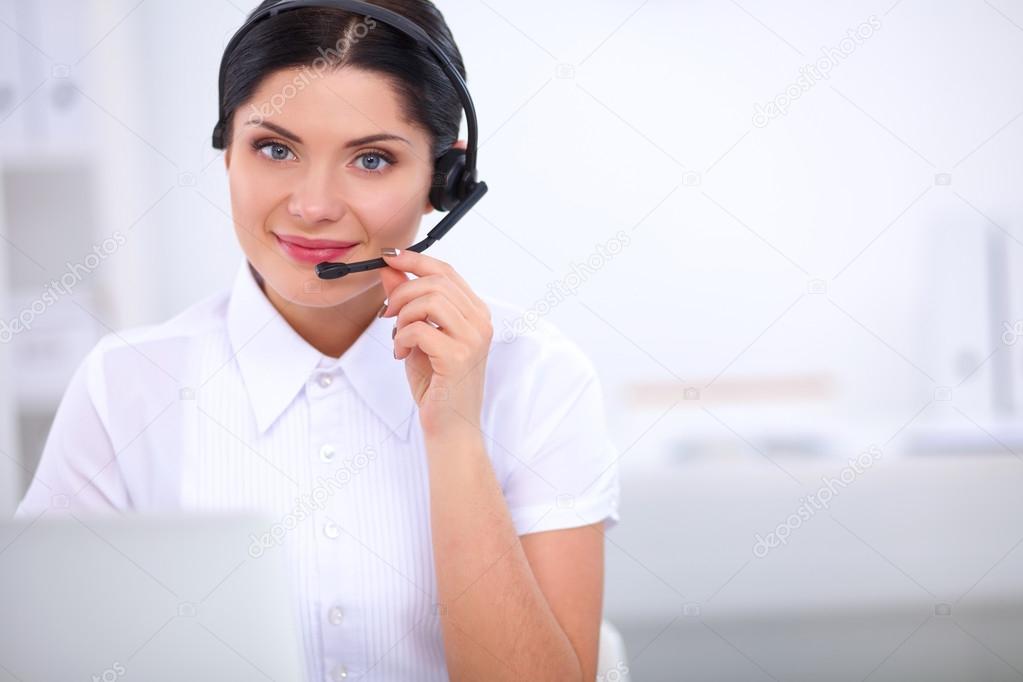 Portrait of beautiful businesswoman working at her desk with headset and laptop