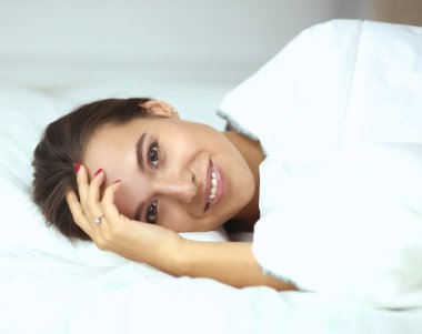 Genç ve güzel bir kadın yatakta yatıyor.