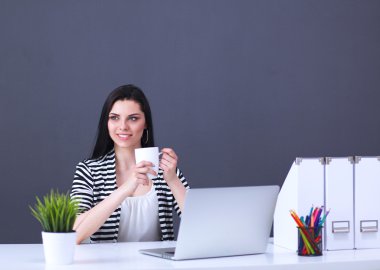 Gri arka planda dizüstü bilgisayarı olan genç bir kadın.