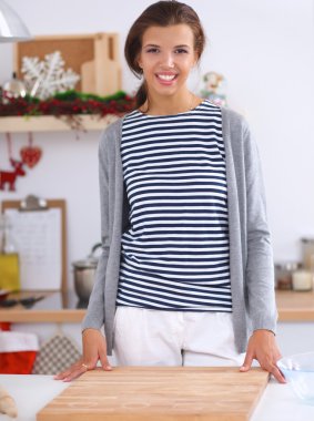 Mutfakta gülümseyen genç bir kadın, Noel arkaplanında.