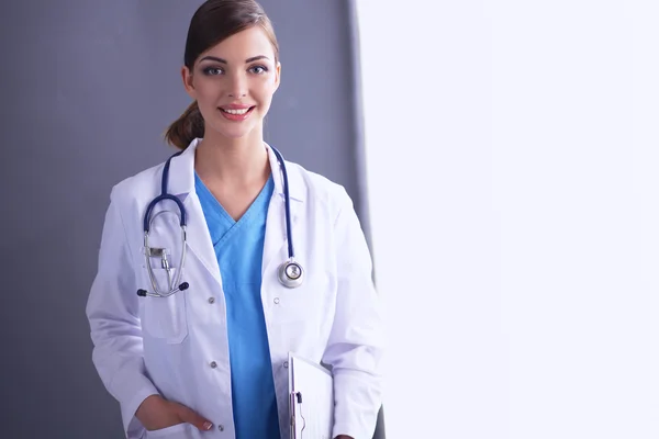 Junger Arzt oder Sanitäter mit Klemmbrett und Stethoskop isoliert auf grauem Hintergrund — Stockfoto