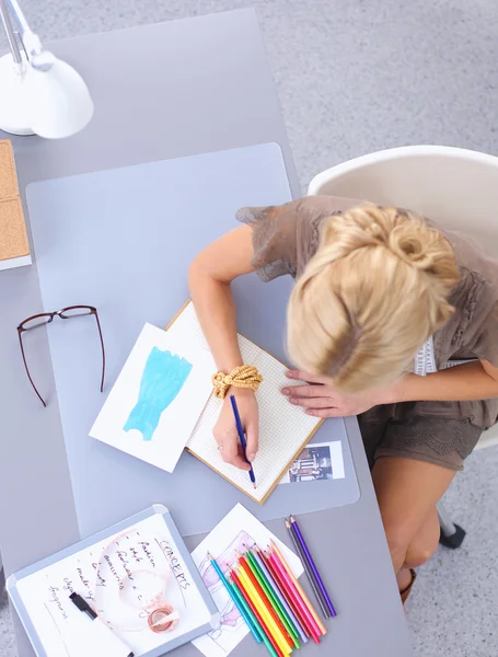 Giovane attraente stilista di moda femminile che lavora alla scrivania dell'ufficio, disegnando mentre parla sul cellulare — Foto Stock