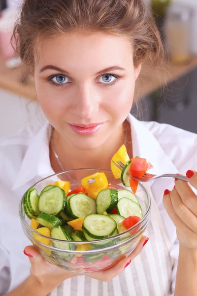 Mujer joven comiendo ensalada fresca en la cocina moderna — Foto de Stock