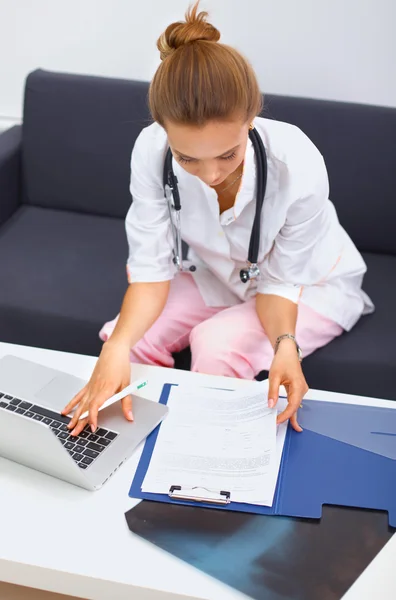 Female doctor sitting at desk explaining medical scan — Stock Photo, Image