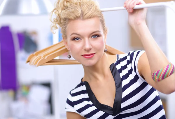 Mooie jonge stylist bij rek met hangers — Stockfoto