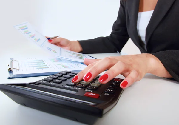 Geschäftsfrau erledigt Büroarbeit am Schreibtisch mit einem Taschenrechner — Stockfoto