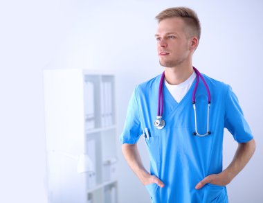 Steteskoplu doktor ayakta, çapraz kollu, beyaz arka planda izole.