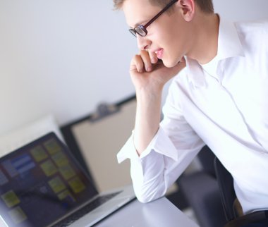 Genç işadamı ofiste çalışıyor, masada oturuyor.