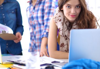 Ofis masasında çalışan genç, çekici bayan moda tasarımcısı, cep telefonuyla konuşurken çizim yapıyor.