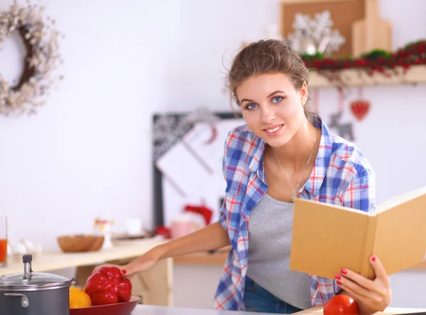 Sorridente giovane donna in cucina, isolata su sfondo natalizio — Foto Stock