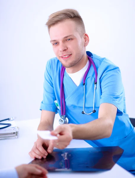 Портрет улыбающегося врача-мужчины с ноутбуком, сидящего за столом в медицинском кабинете — стоковое фото