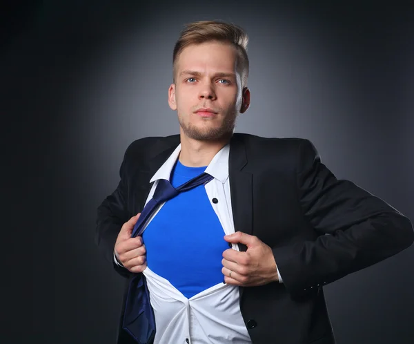 Young businessman acting like a super hero and tearing his shirt, isolated on gray background — Stock Photo, Image