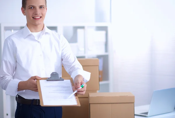 Delivery man with  parcel and a tablet standing in office — Stock Photo, Image