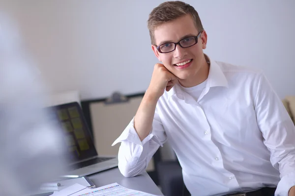 Молодий бізнесмен, що працює в офісі, стоїть біля столу — стокове фото