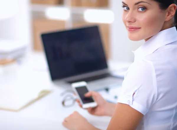 Zakenvrouw stuurt bericht met smartphone zittend op kantoor — Stockfoto