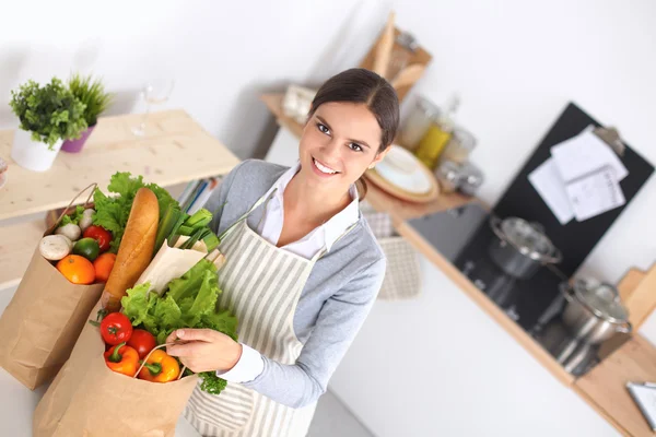 Kvinna med shoppingväskor i köket hemma, stående nära skrivbordet — Stockfoto