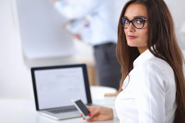 Attraktive Geschäftsfrau sitzt auf Schreibtisch im Büro — Stockfoto