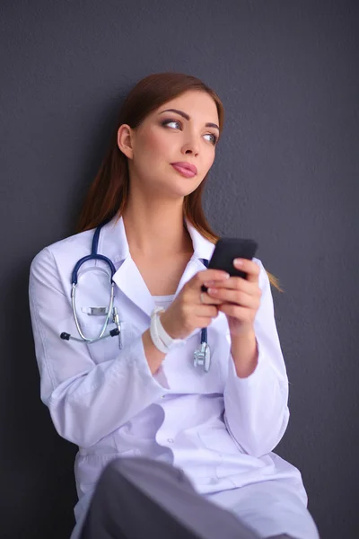 若い女性の医者はあなたの携帯電話で床に座って — ストック写真