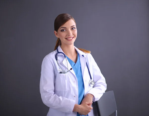 Beautiful female doctor standing near stool isolated grey background — Stock Photo, Image