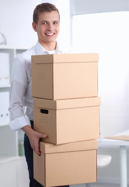 Young Man holding a stack of cardboard boxes standing in office — Stock Photo, Image