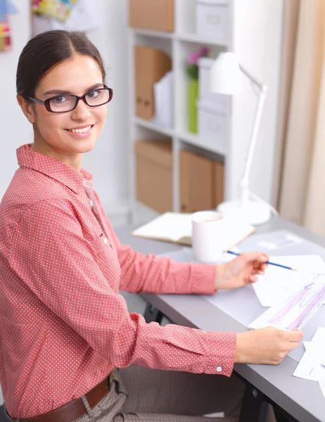 Junge attraktive Modedesignerin arbeitet am Schreibtisch und zeichnet, während sie mit dem Handy spricht — Stockfoto