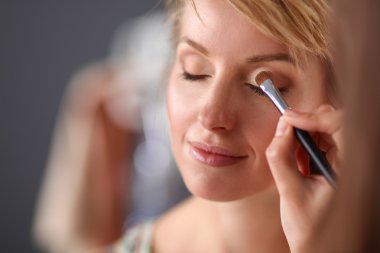 Kadından profesyonel makyaj yapan sanatçı.