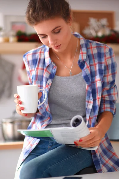 Donna che legge rivista In cucina a casa — Foto Stock