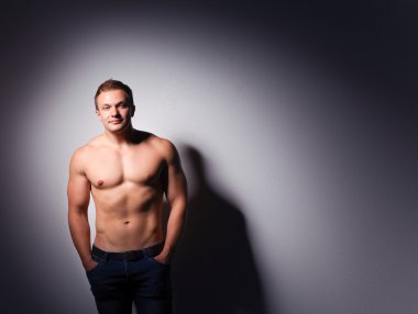 Karanlık bir arka plan üzerinde ayakta sağlıklı kas genç adam