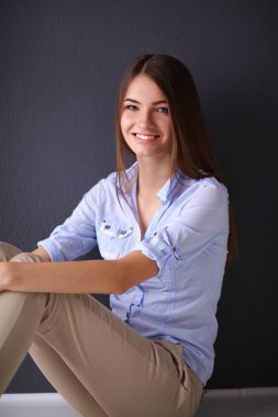 Young woman sitting on the floor near dark wall clipart