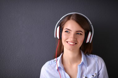 Duvara yakın katta oturan kulaklıklar ile gülümseyen kız