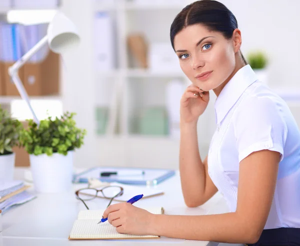 Attractive businesswoman sitting  on desk in the office — Stock Photo, Image