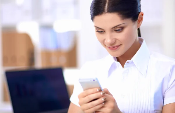 Empresaria enviando mensaje con teléfono inteligente sentado en la oficina — Foto de Stock