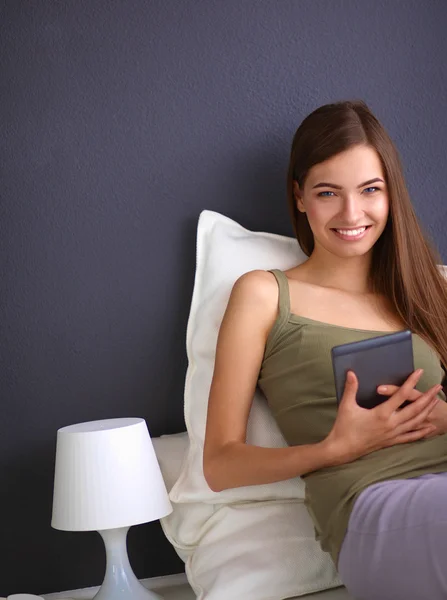 Mujer morena bonita sentada en el suelo con una almohada y mesa de avión — Foto de Stock